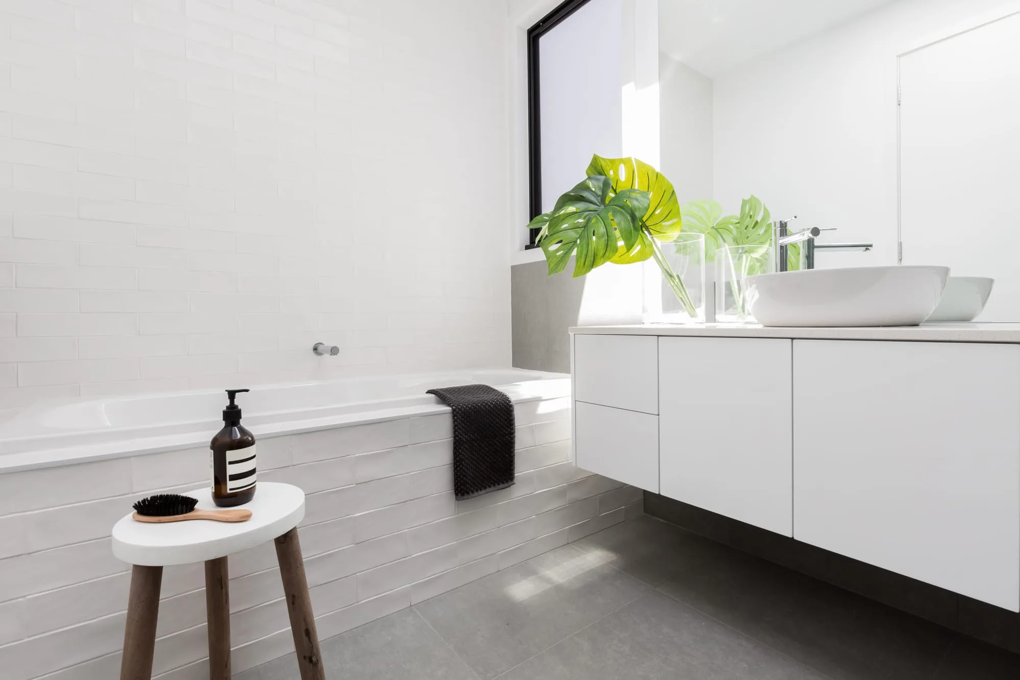 Bright renovated bathroom with a monstera plant and floating vanity