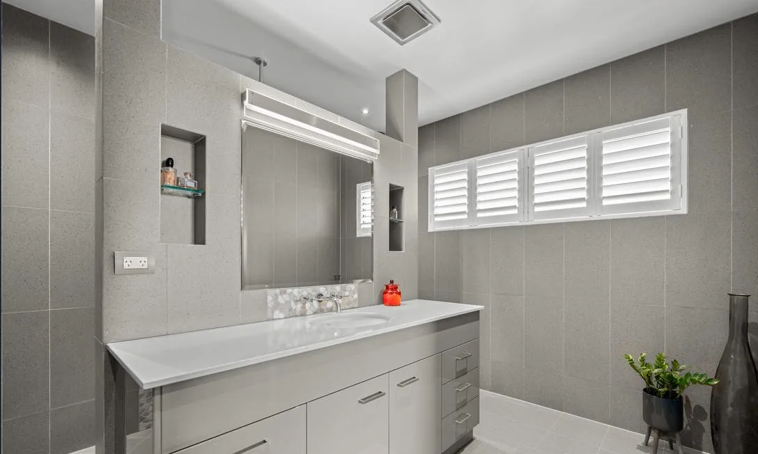 Grey-tiled bathroom with plantation shutters