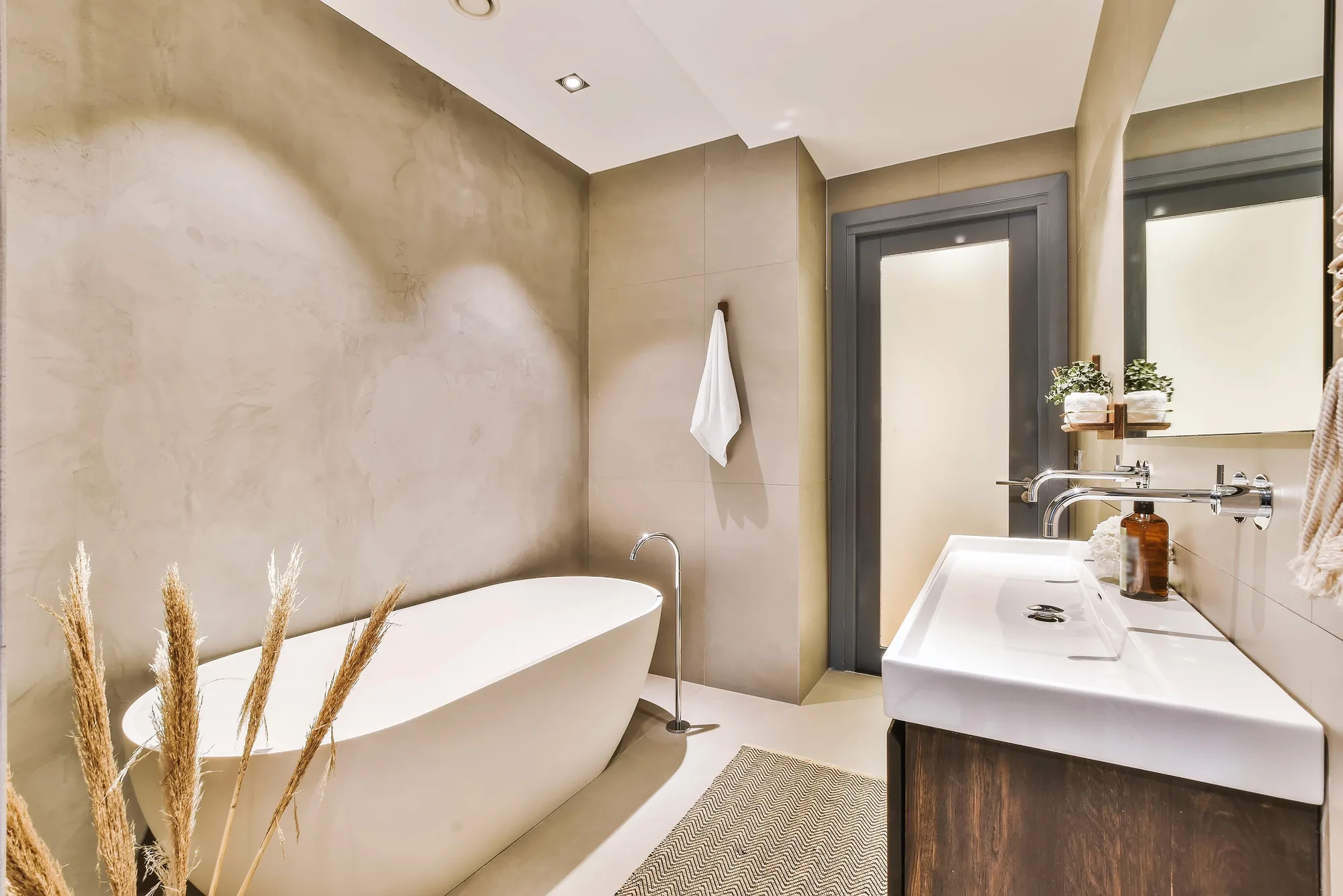 Freestanding bath with warm plaster wall and dried pampas grass