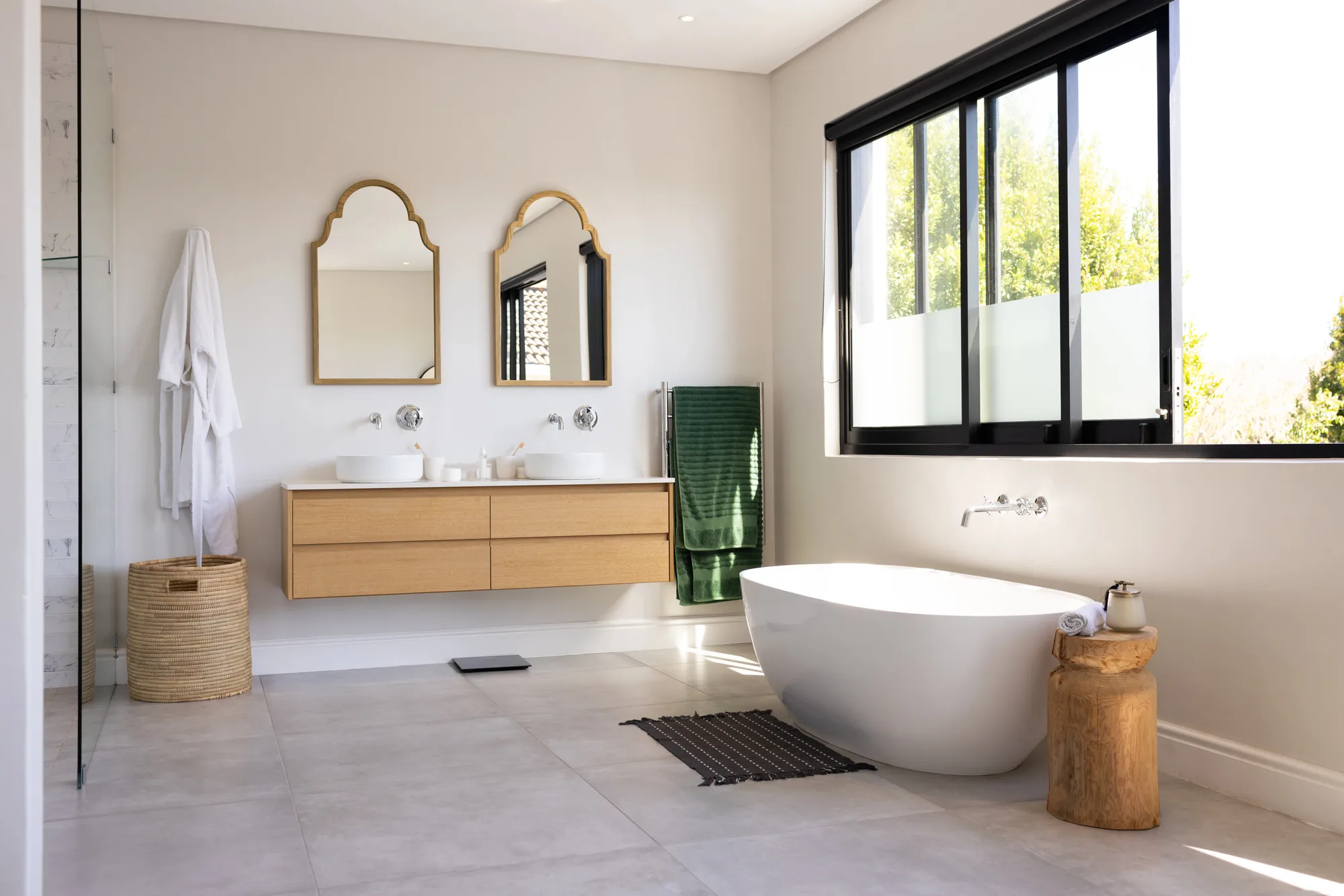 Luxury double-vanity bathroom with arched mirrors and freestanding tub