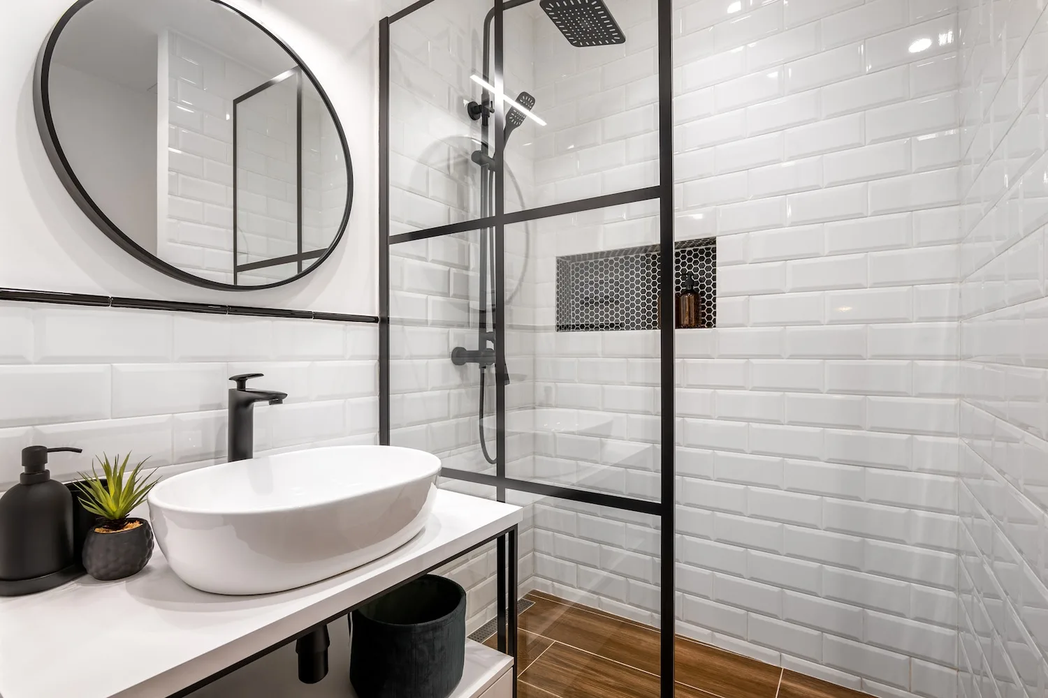 Crisp white subway-tile shower with round black-framed mirror